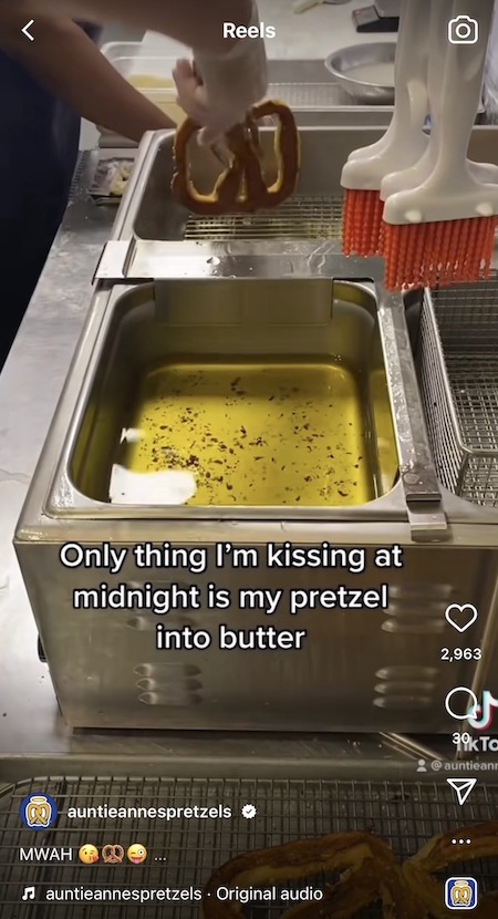 An Auntie Anne's Instagram Reel showing an Auntie Anne's pretzel maker dipping a pretzel into butter, and text on the screen that says Only thing I'm kissing at midnight is my pretzel into butter.